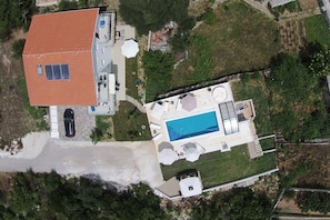Vista aérea de una casa con piscina, terraza cubierta y garaje.