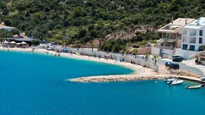 A coastal area with a beach, a rocky outcrop, and buildings with balconies overlooking the sea. - Luxury villa with private heated pool and sea view 3 (Marina)