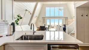 A kitchen with a large island, a built-in oven, and a view to a dining area. - Roomy Chalet-Style Beachfront Condo with Private Beach Access by RedAwning (Fernandina Beach)
