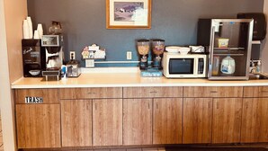 Eine Küchenzeile mit Kaffeemaschine, Mikrowelle und Mülleimer.