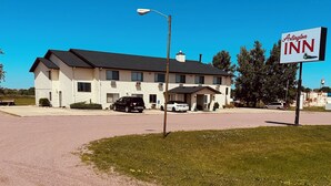 Ein Motel mit einem Schild, auf dem 'Arlington INN' steht, vor einem zweistöckigen Gebäude mit flachem Dach und einem überdachten Parkbereich.