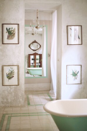 A bathroom with a bathtub, a mirror, and framed pictures on the walls. - Coqui Coqui Meson de Malleville - Valladolid (Valladolid)