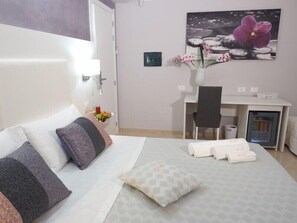 A hotel room with a bed, a desk, a chair, and a small refrigerator. - Pepè Accommodation (Parghelia)