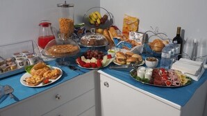 A buffet table with various food items, including fruits, sandwiches, and a bottle of wine.