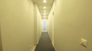 A narrow hallway with carpeted floors and light-colored walls.