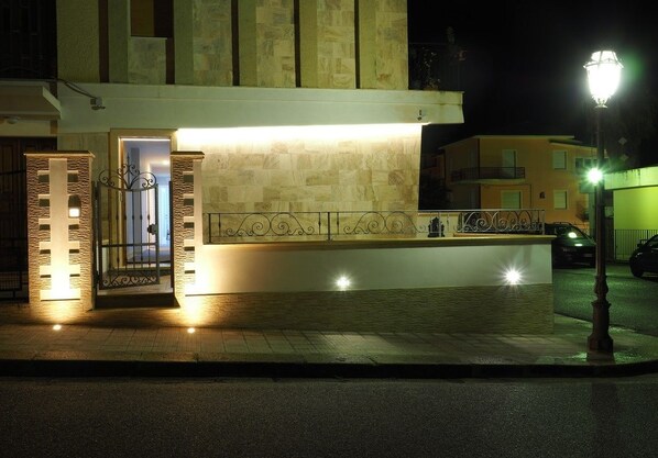 A building with a gated entrance and a well-lit facade at night. - Pepè Accommodation (Parghelia)