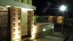 A building with illuminated stone pillars and a balcony railing.