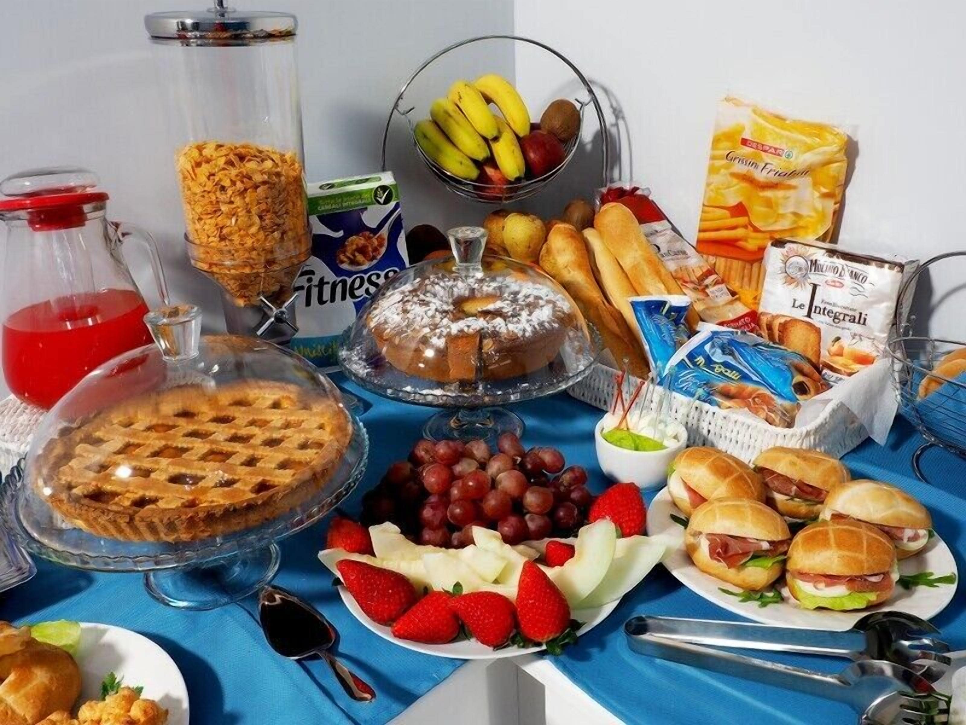 A buffet table with various food items including a pie, sandwiches, fruits, and snacks.