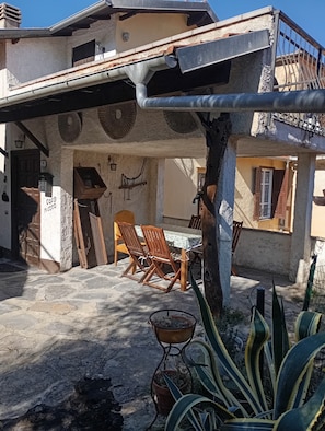 A rustic building with a covered patio, stone flooring, wooden furniture, and potted plants. - TYPICAL  INDEPENDENT RESIDENCE, SWIMMING POOL / RELAXING OASIS, BARBECUE, DEHOR (Lecchiore)