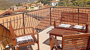 A terrace with wooden furniture and a view of a hillside village. - TYPICAL  INDEPENDENT RESIDENCE, SWIMMING POOL / RELAXING OASIS, BARBECUE, DEHOR (Lecchiore)