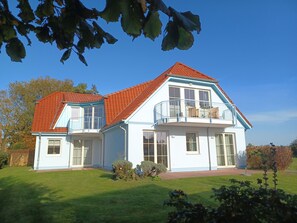 A two-story house with a red-tiled roof, large windows, and a balcony. - At the Bodden Meadows I (Wustrow)