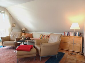 A living room with a sofa, armchair, coffee table, and a bookshelf. - At the Bodden Meadows I (Wustrow)