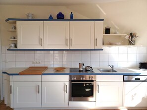A modern kitchen with white cabinets, a stainless steel oven, and a blue countertop. - At the Bodden Meadows I (Wustrow)