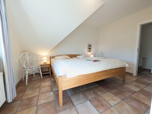 Ein Schlafzimmer mit einem Holzbett, einem Nachttisch mit Lampe, einem Sessel und einer Heizung.