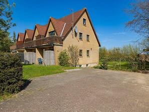 A two-story house with a brick exterior, a sloped roof, and a gravel driveway.