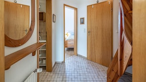 A hallway with wooden doors, a tiled floor, and a view through an open door. - Pühler - Apartment Buchfink - FW chaffinch (Kronsgaard)