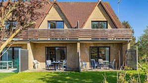 A two-story house with a brick exterior, a tiled roof, and a covered patio area with outdoor seating. - Pühler - Apartment Buchfink - FW chaffinch (Kronsgaard)