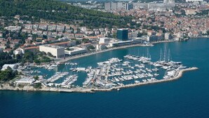 An aerial view of a marina with numerous boats docked, surrounded by a coastal cityscape with buildings and greenery. - Luxury villa with private heated pool and sea view 2 (Marina)