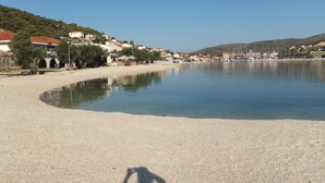 A beach with a pebble shore, a clear sky, and buildings in the background. - Luxury villa with private heated pool and sea view 2 (Marina)
