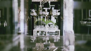 A table set with glassware, a pitcher, and a vase of flowers, with a chandelier above. - Coqui Coqui Valladolid (Valladolid)