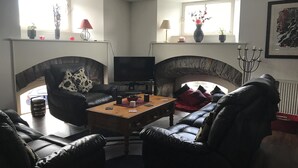 Un salon avec une cheminée, des meubles en cuir, un téléviseur et une table basse.