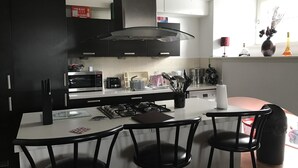 Une cuisine moderne avec un îlot central, des chaises noires et un four à micro-ondes.