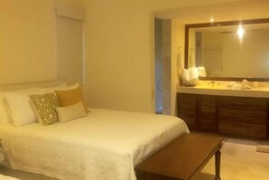 Une chambre d’hôtel avec un lit, une table de chevet, un grand miroir et une commode en bois.