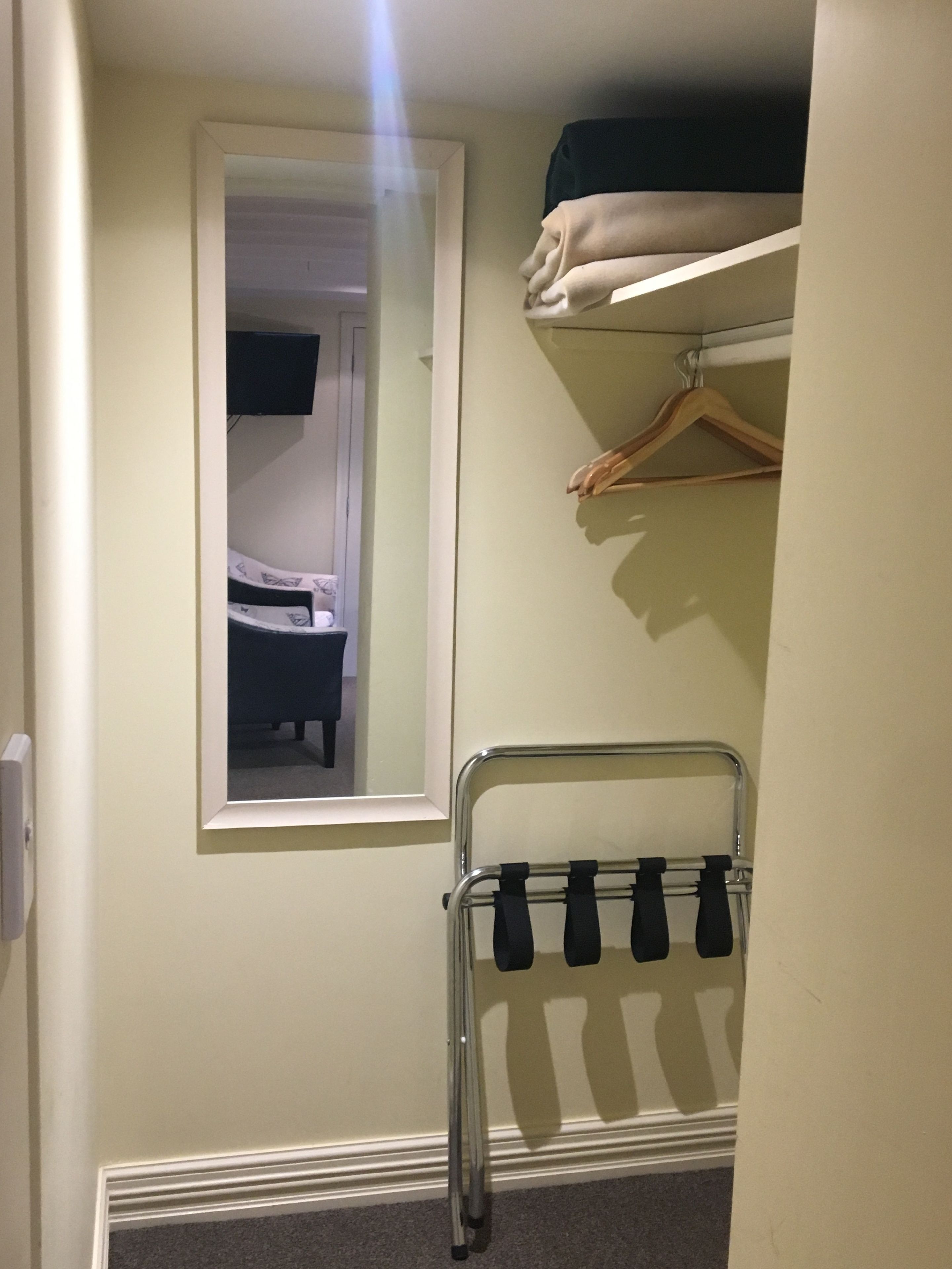 Une pièce comprenant un lit, un miroir, un porte-manteau et une porte.