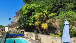 A swimming pool with a wooden deck, lounge chairs, and a statue. - Character house in Montignac Lascaux (Montignac)