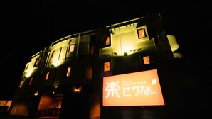 A building with illuminated signage at night, featuring a prominent sign with Japanese characters and the words "HOTEL" and "SERIES". - HOTEL Rakuserina (Fuefuki)