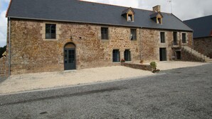 A stone building with a grey roof, a central entrance, and a small garden area. - Comfortable cottage in Saint-Pair-sur-Mer, near Granville beaches (Saint-Pair-sur-Mer)