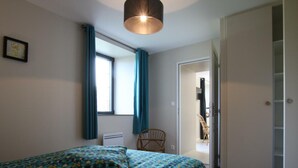 A bedroom with a bed, a window with curtains, a chair, and a door leading to another room. - Comfortable cottage in Saint-Pair-sur-Mer, near Granville beaches (Saint-Pair-sur-Mer)