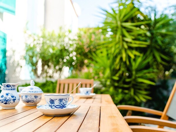 A wooden table with a teapot, cups, and saucer set.