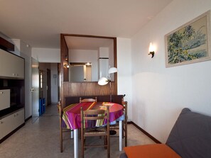 A compact living space with a dining area, a sofa, and a painting on the wall.