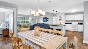 Een moderne keuken met witte kasten, een centraal eiland en een eethoek met een geruite tafelkleed.