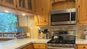 A kitchen with wooden cabinets, stainless steel appliances, and a dishwasher. - Charming, Cozy, & Peaceful Mountain Getaway for Family & Friends (Shaver Lake)