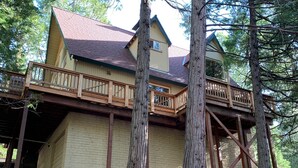 A two-story house with a wooden deck and a red roof. - Charming, Cozy, & Peaceful Mountain Getaway for Family & Friends (Shaver Lake)