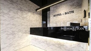 Ein Empfangsschalter mit Wandverkleidung aus Marmor und der Aufschrift 'HOTEL BATH' und 'INFORMATION'.
