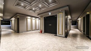Ein Hotelkorridor mit modernem Design, ein Marmorboden, eingelassene Beleuchtung und ein Feuerlöscher in der Nähe des Eingangs.