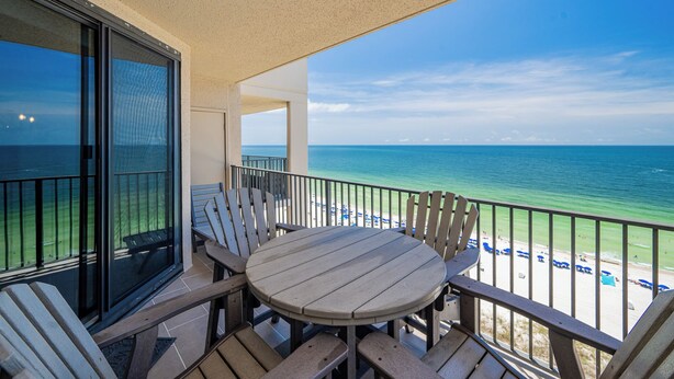 Un balcon avec une table et des chaises donnant sur une plage.
