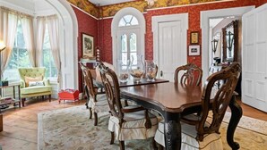A dining room with a large wooden table, ornate chairs, and a chandelier.