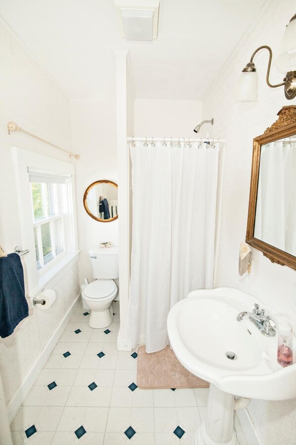 A bathroom with a toilet, sink, and shower curtain.