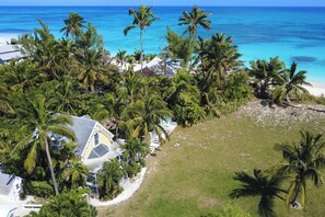 Tropisch resort met uitzicht op het strand, palmbomen en een huis met een bijzonder dakontwerp.