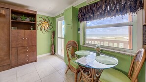 A dining area with a glass table, wicker chairs, and a view of the beach. - DIRECTLY ON BEACH!  STUDIO Sleeps 2   Full Kitchen, Free parking, Heated Pool (Pompano Beach)
