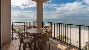 A balcony with a table and chairs overlooking a beach.