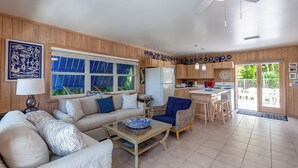 Amplia sala de estar con sofá, una mesa de centro y un comedor con una cocina al fondo.