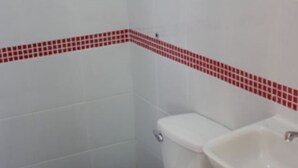 A small bathroom with a toilet, sink, and blue-tiled floor. - Bakasyunan Inn Laoag (Laoag)