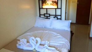 A hotel room with a bed, white pillows, a decorative wall panel, and a door. - Bakasyunan Inn Laoag (Laoag)