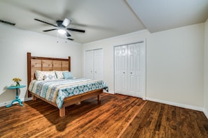 A bedroom with a wooden bed, white walls, and a ceiling fan. - Walking distance to the Gaylord and backs to Lake Grapevine! (Grapevine)
