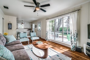 A spacious living room with a sofa, coffee table, and chairs. A kitchen is visible in the background with white cabinets and a dining area. - Walking distance to the Gaylord and backs to Lake Grapevine! (Grapevine)
